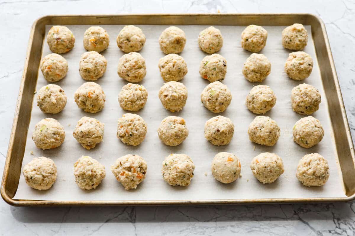 Angle shot of the balls evenly spaced on a cookie sheet. 