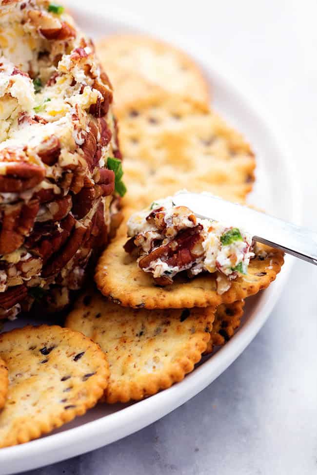 Close view of a cracker with cheeseball spreading on top.