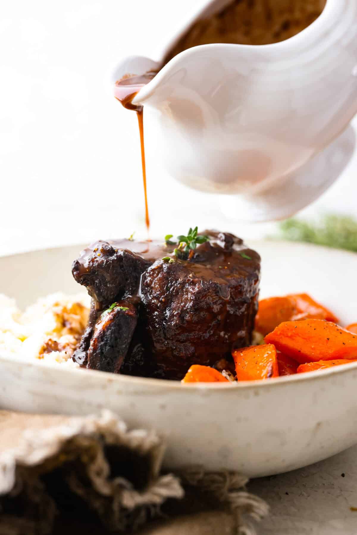 Close view of the gravy pouring over beef short ribs.