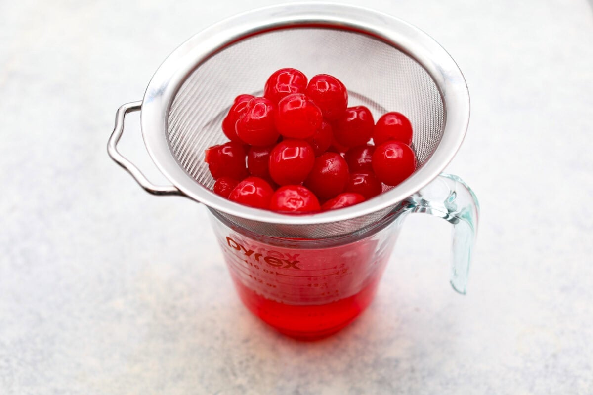 Angle shot of cherries in a strainer over a measureing cup. 