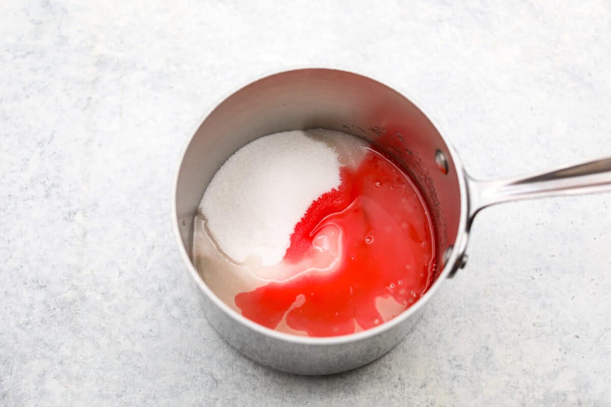 Overhead shot of sugar, water corn syrup and maraschino liquid in a saucepan. 