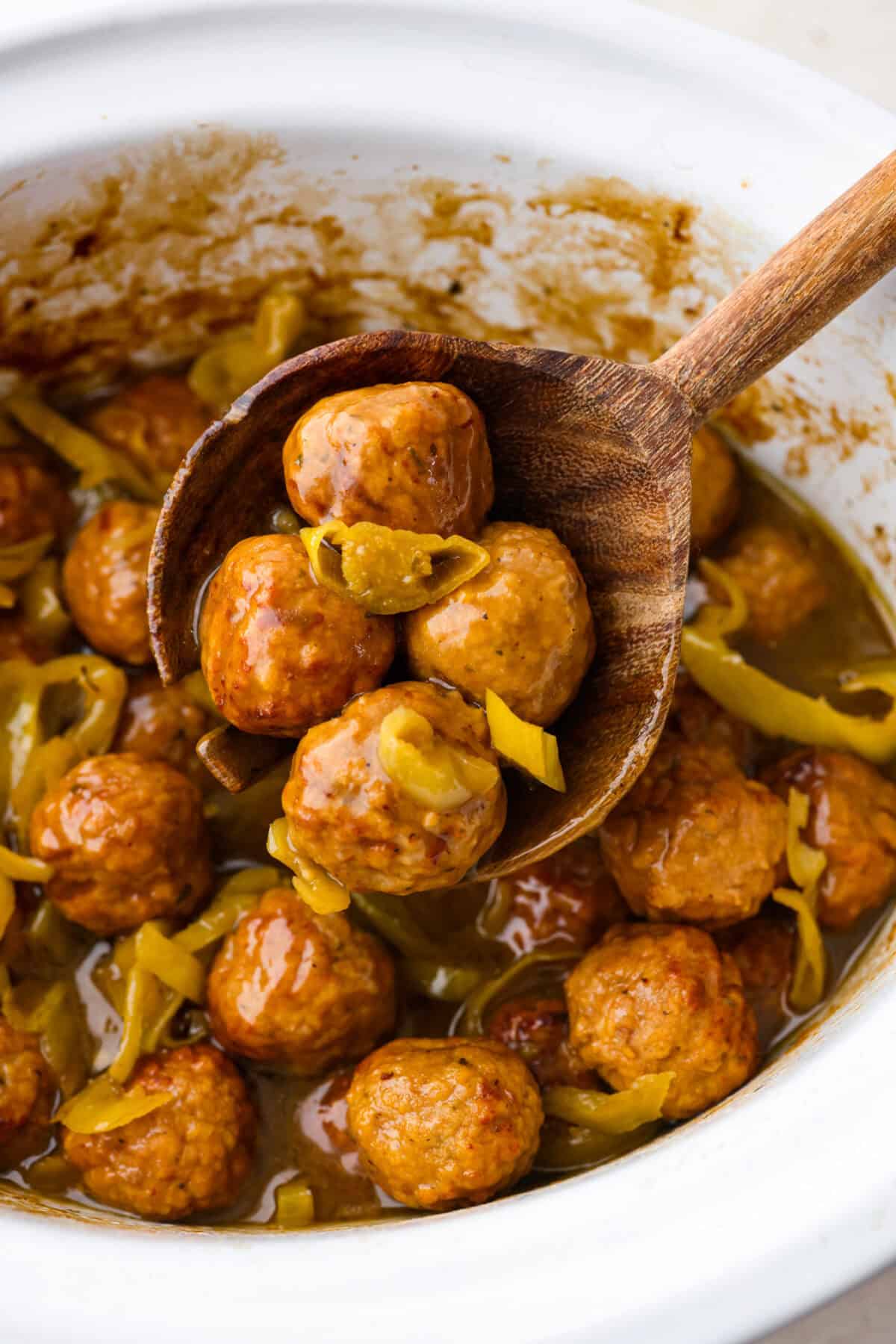 Close up shot of crockpot Mississippi meatballs in a wooden serving spoon. 