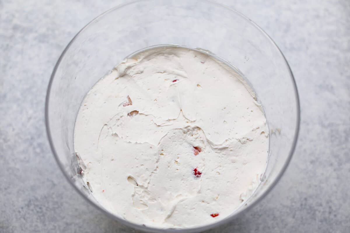 Overhead shot of the cream cheese and whipped topping mixture on top of the cake and strawberries. 