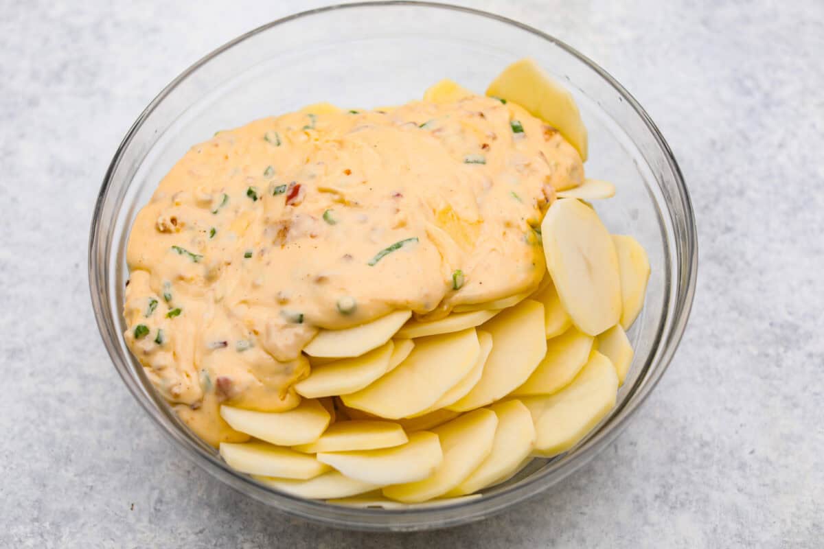 Overhead shot of the cheesy sauce poured over the sliced potatoes. 