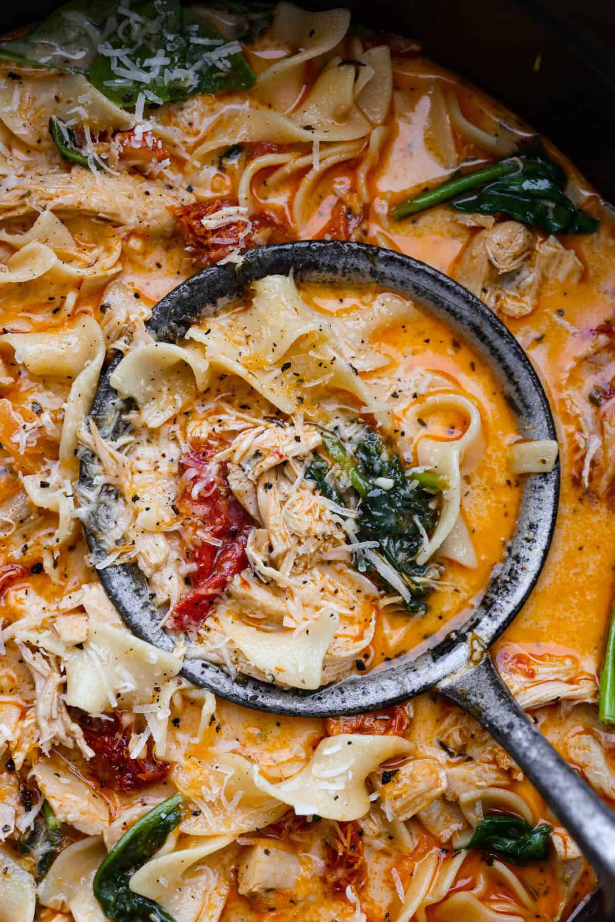 Close view of a ladle full of marry me chicken soup.