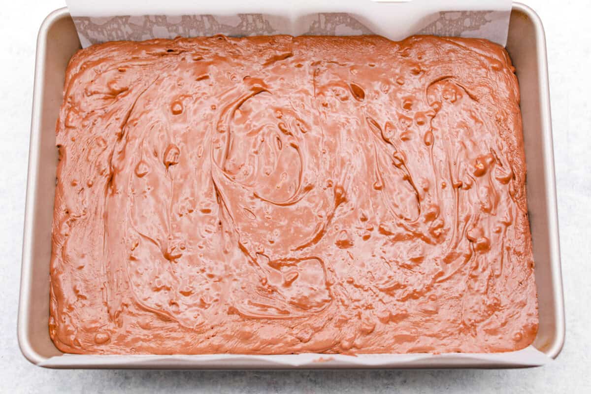 Overhead shot of the million dollar fudge mixture poured evenly into a pan with parchment paper. 