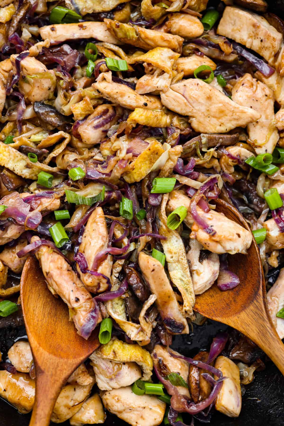 Close up shot of Moo Shu Chicken with two wooden serving spoons. 