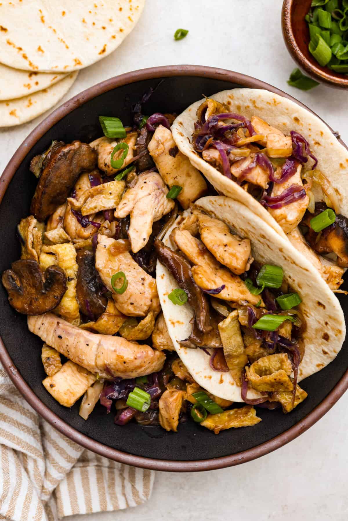 Overhead shot of plated Moo Shu chicken with some in tortillas. 