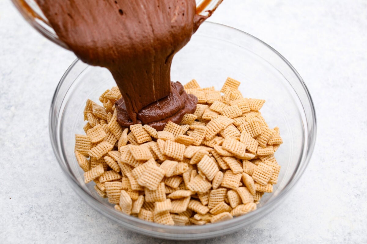 Overhead shot of someone pouring the chocolate and marshmallow mixture over the cereal. 