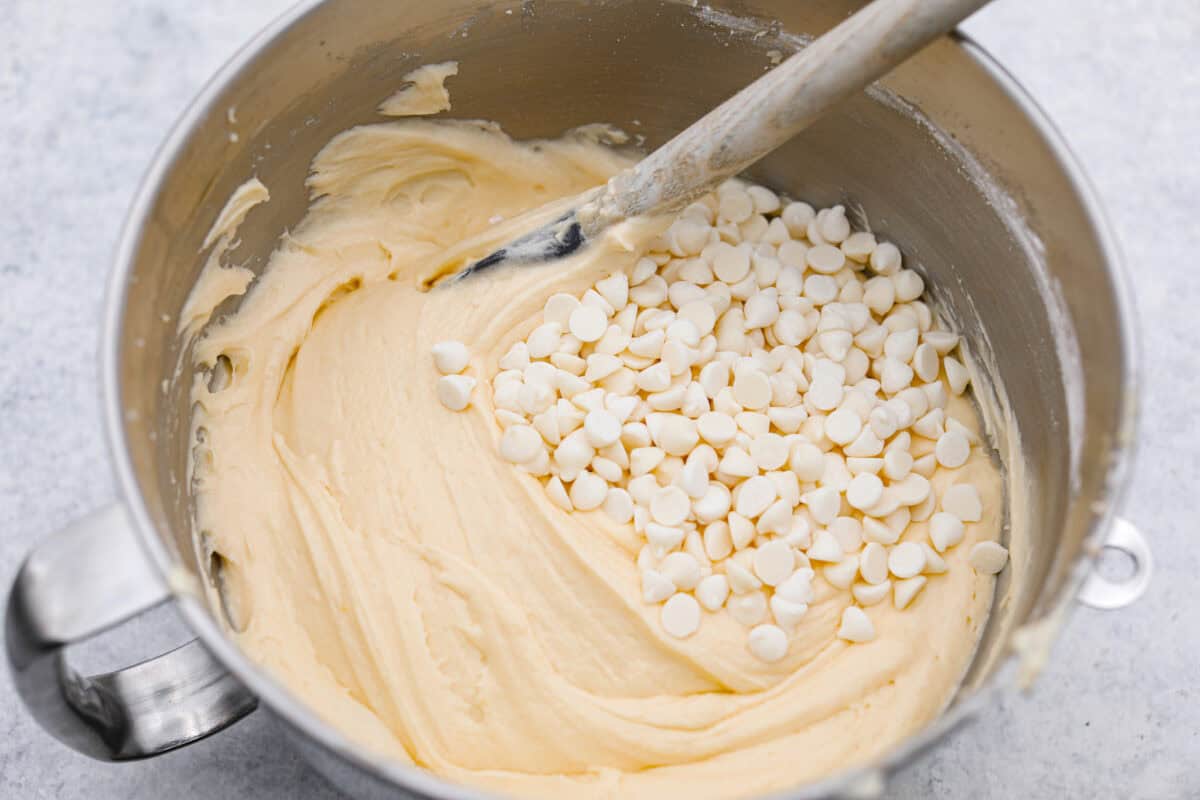 Overhead shot of tom cruise coconut cake batter with white chocolate chips being folded in. 