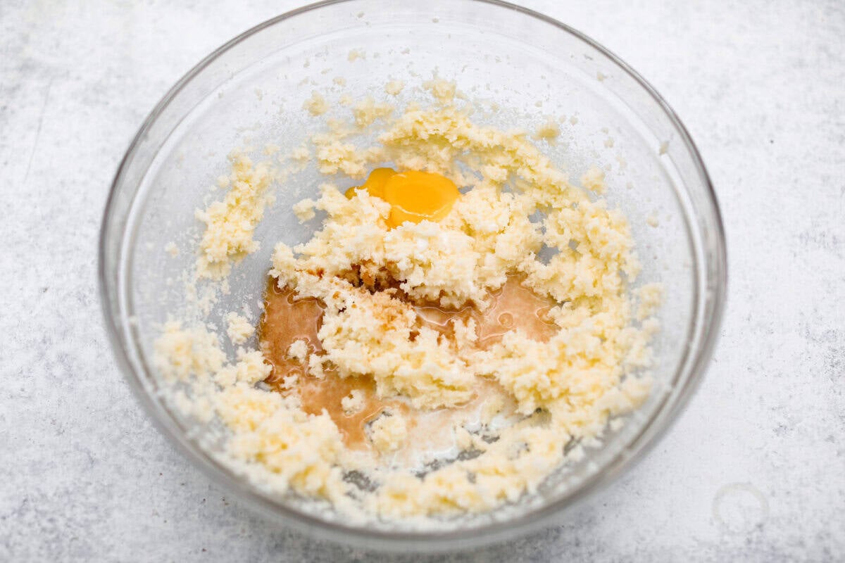 Overhead shot of creamed butter and sugar in bowl with vanilla, milk and egg yolk.