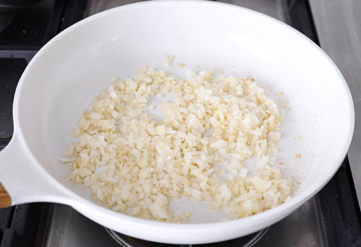 Angle shot of the onions cooking in the sesame oil in a skillet. 