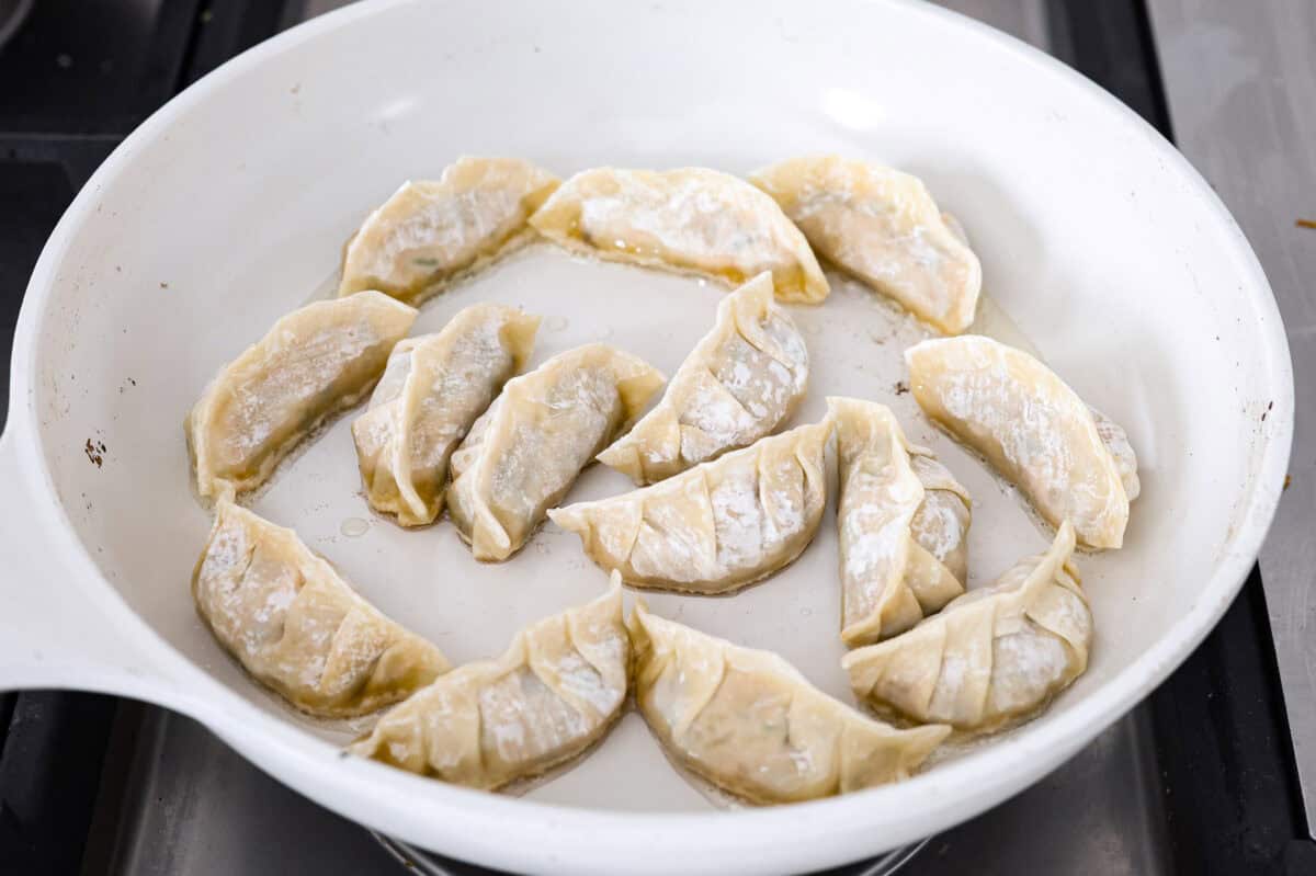 Angle shot of the vegetable dumplings in a skillet with hot oil. 