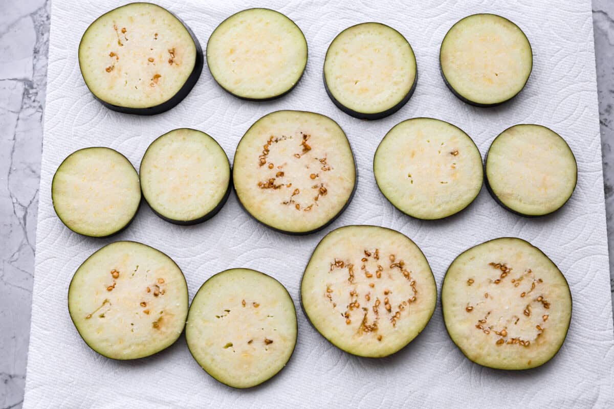 Overhead shot of sliced eggplant on paper towels. 