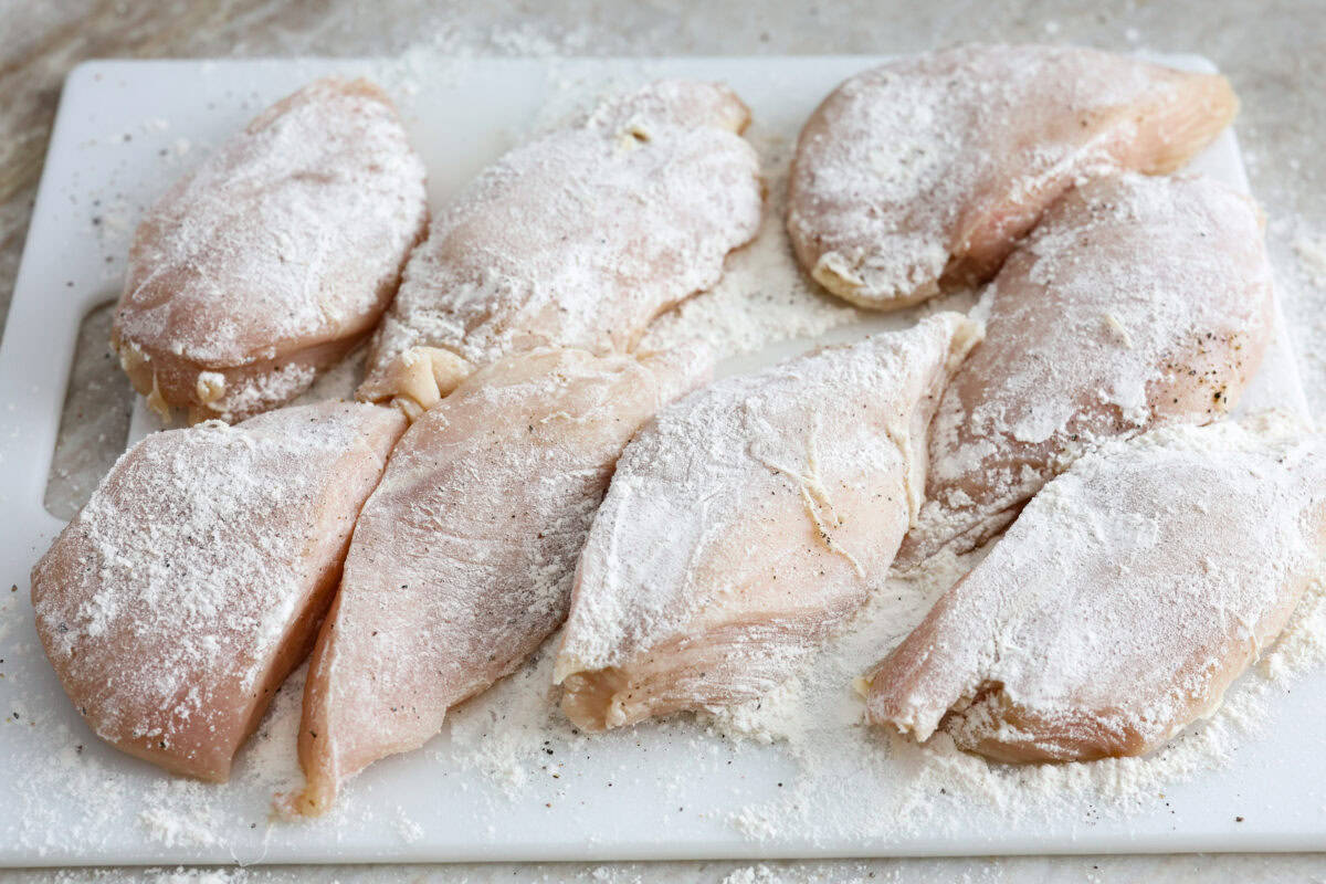 Overhead shot of chicken seasoned with salt and pepper and coated in flour. 