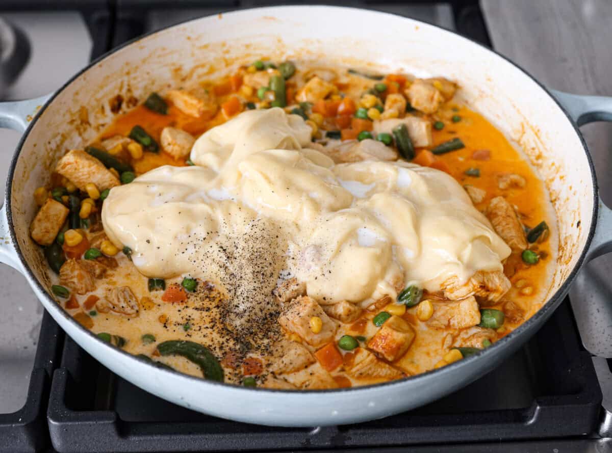 Angle shot of the veggies added in with the chicken and onion mixture with milk, soup and salt and pepper over the top. 