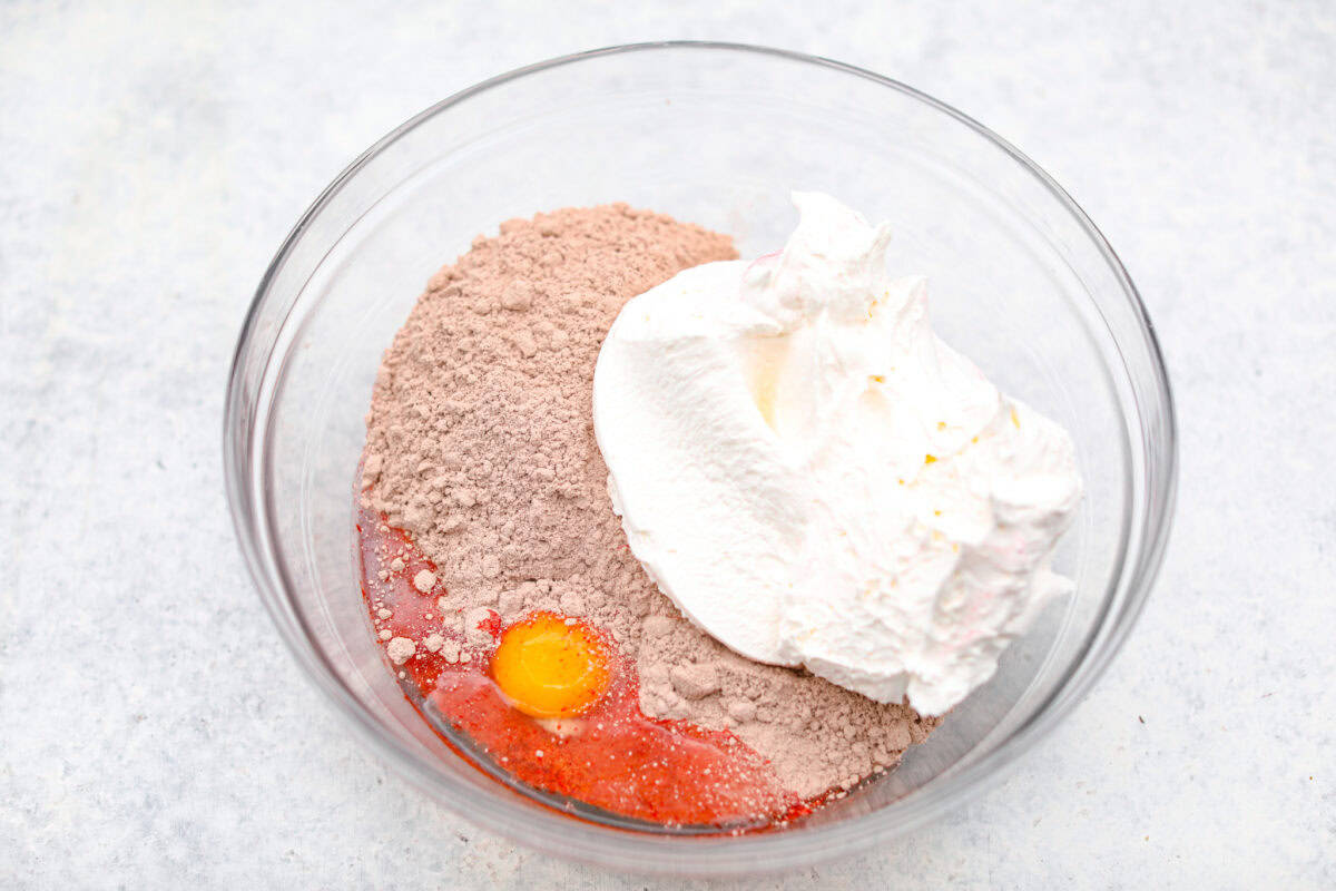 Overhead shot of cake mix, egg and cool whip in a mixing bowl. 