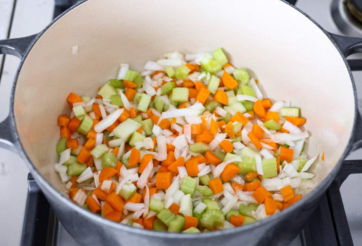 Overhead shot of vegetables cooking in olive oil in a pot. 