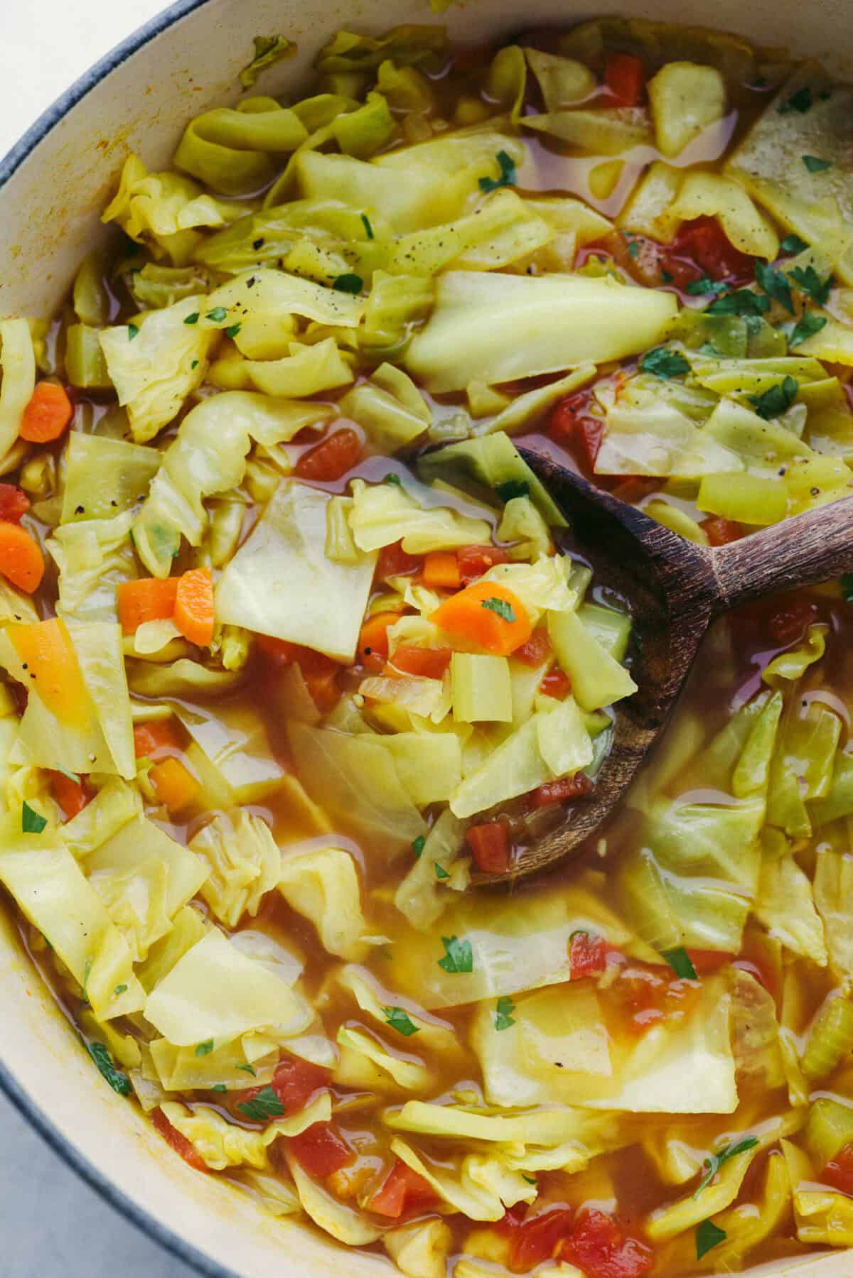 Close up shot of detox cabbage soup with wooden serving spoon. 