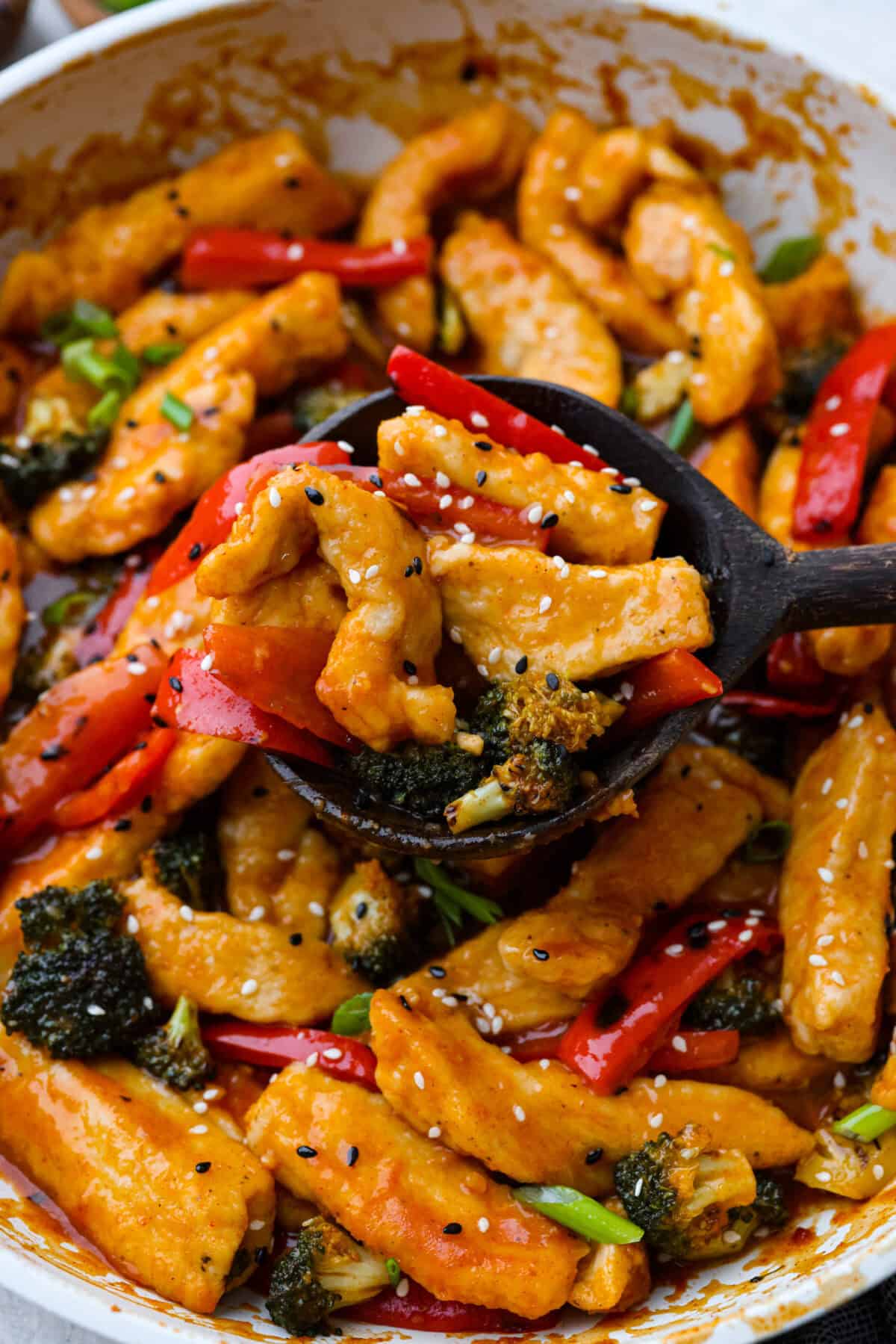 Close view of Hunan chicken on a wooden serving spoon.