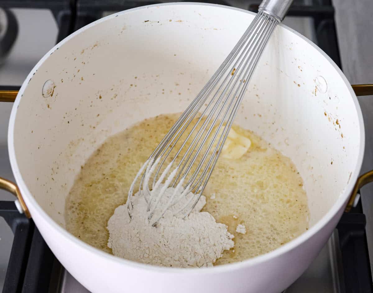 Angle shot of flour being whisked into  the melted butter.