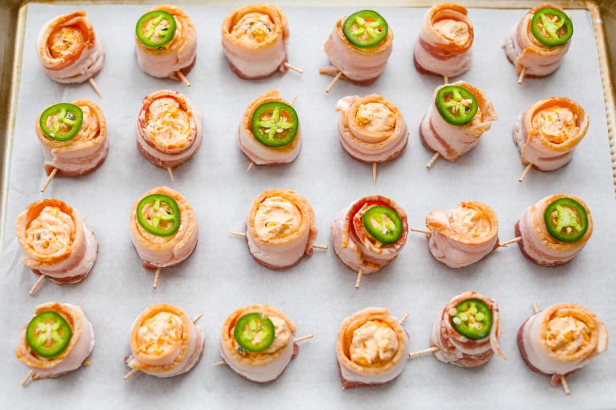 Overhead shot of the filled, bacon wrapped sausage cups. Some of the pig shots have a slice of jalapeño on top. 