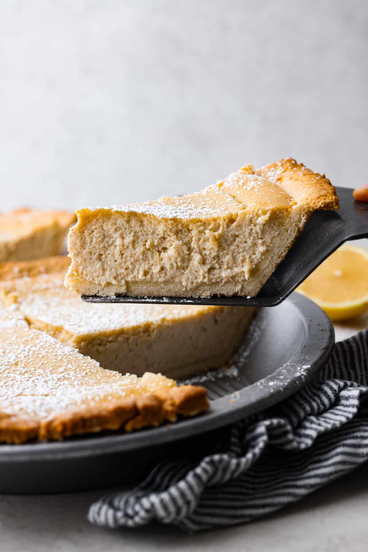 Side shot of a slice of ricotta pie being lifted out of the whole pie pan. 