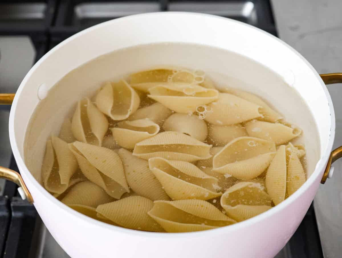 Angle shot of large pasta shells being cooked in boiling water. 