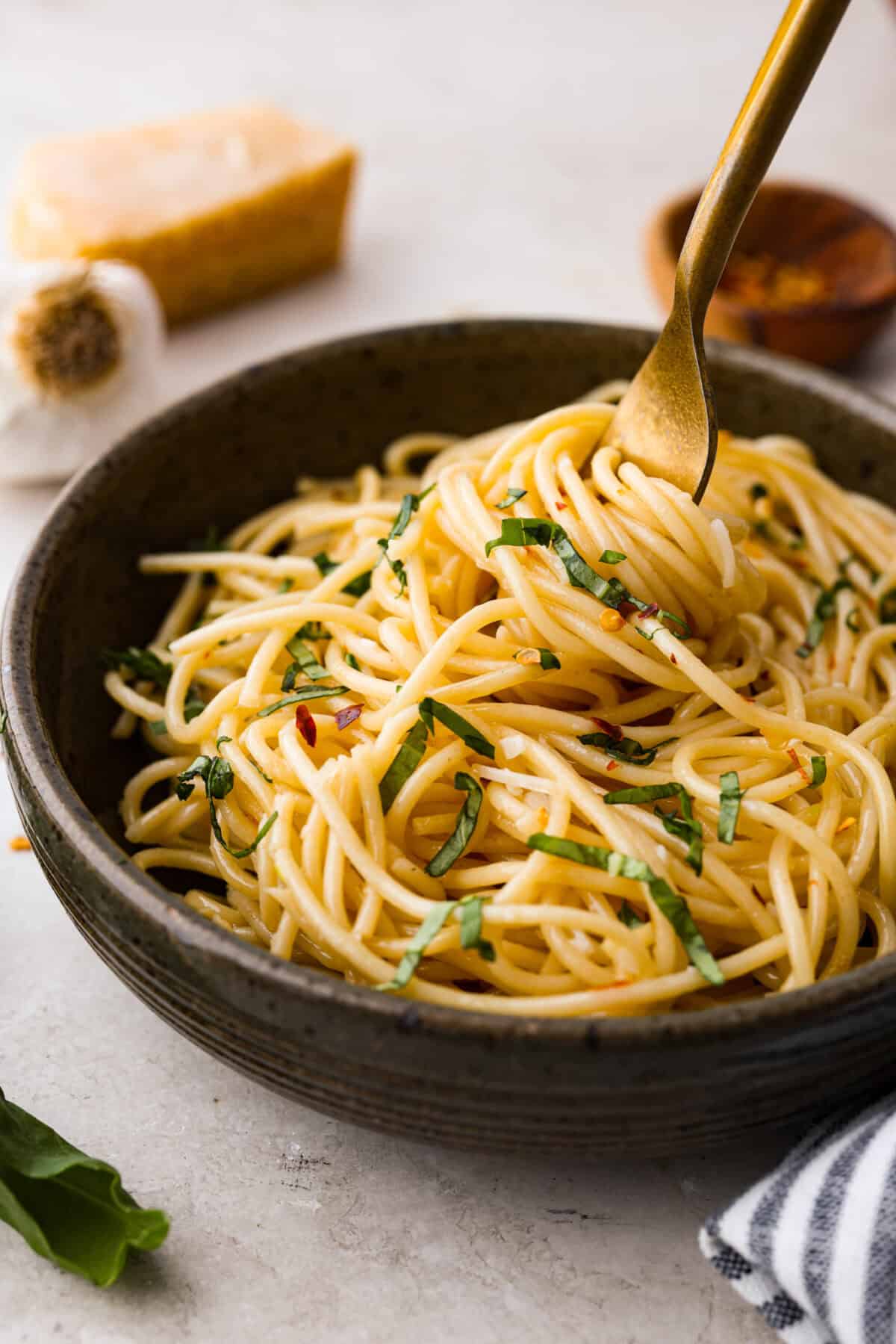 Angle shot of plated spaghetti aglio e olio with a golden fork in it. 