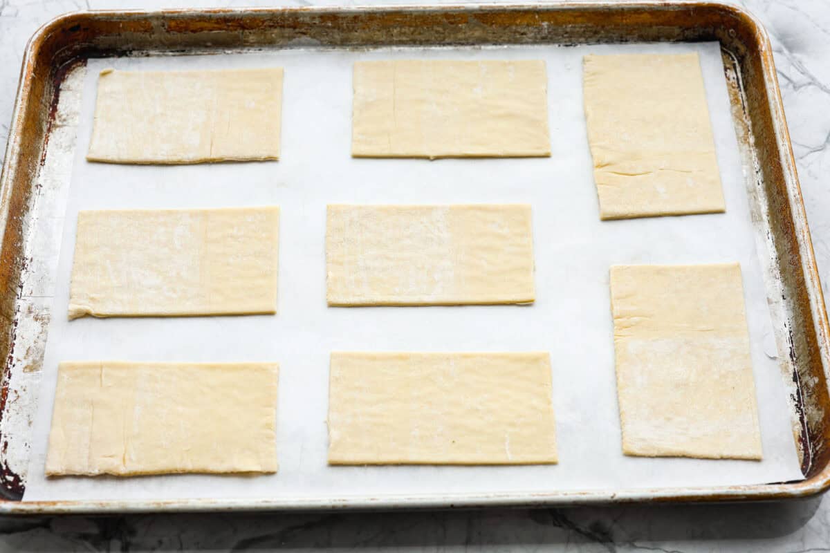 Overhead shot of puff pastry cut into rectangles and placed on a cookie sheet. 