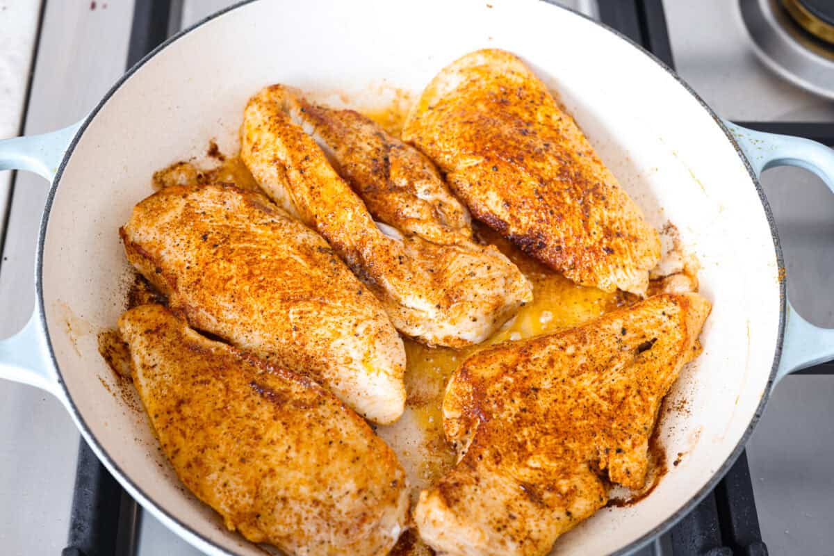 Creamy Cajun Chicken is the perfect combination of bold, zesty flavors and rich, velvety sauce. Juicy, tender chicken is coated in a perfectly spiced Cajun seasoning and simmered in a luscious, creamy sauce that’s packed with flavor. Overhead shot of seasoned chicken cooking in a skillet.