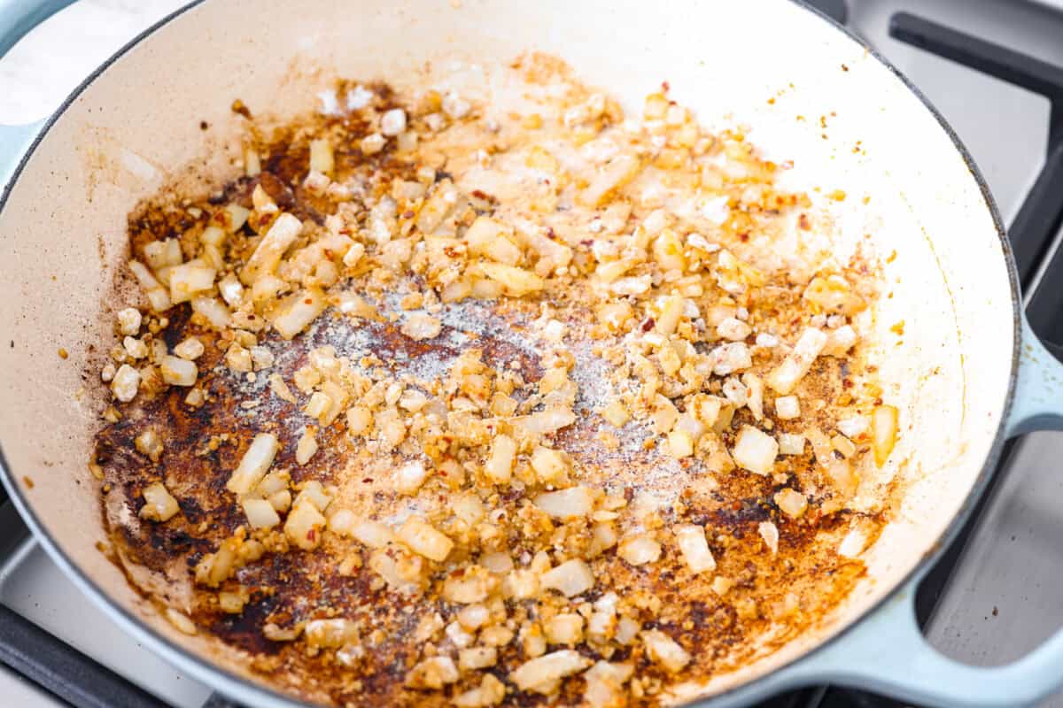 Creamy Cajun Chicken is the perfect combination of bold, zesty flavors and rich, velvety sauce. Juicy, tender chicken is coated in a perfectly spiced Cajun seasoning and simmered in a luscious, creamy sauce that’s packed with flavor. Overhead shot of onions and garlic sautéing in the skillet.