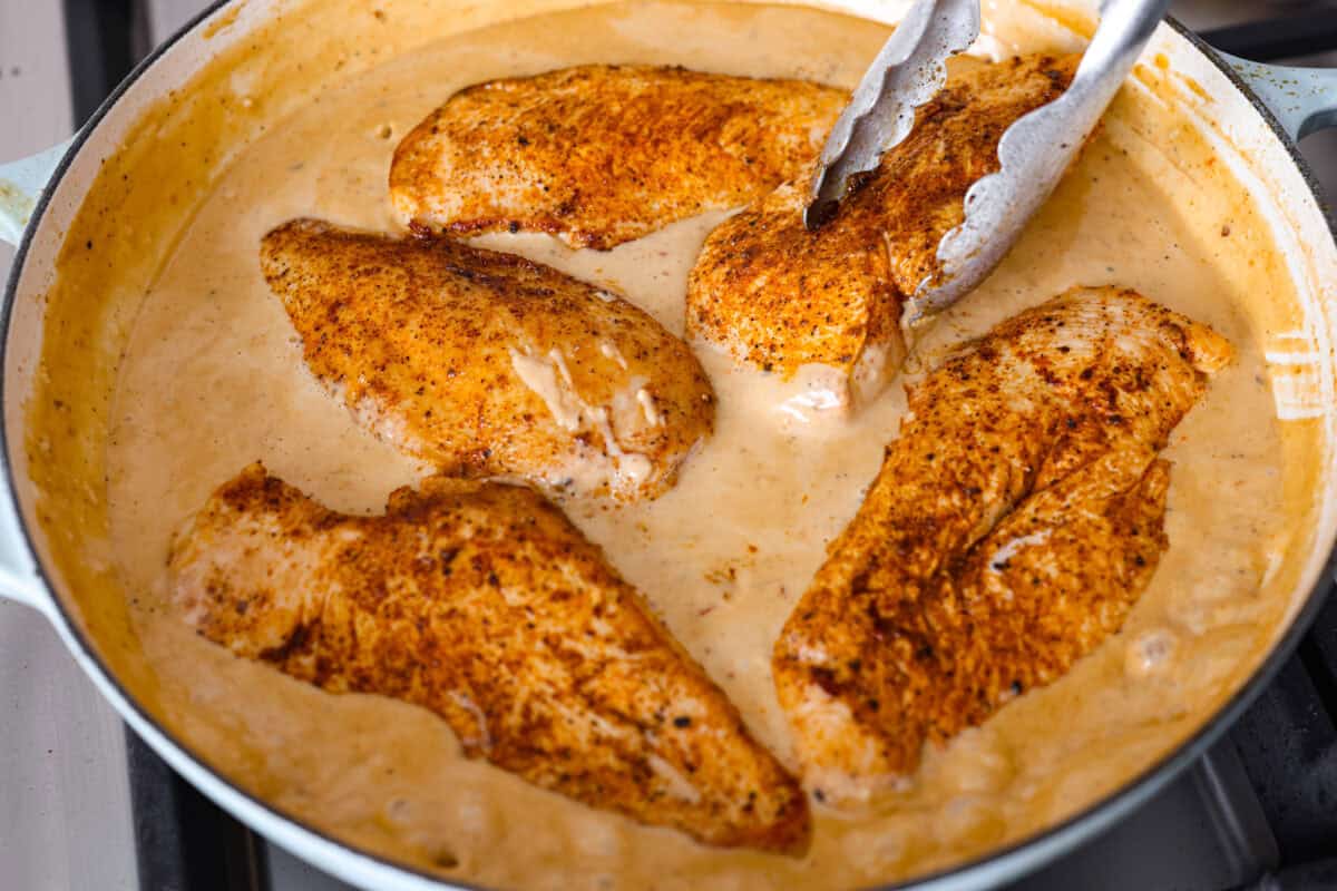 Creamy Cajun Chicken is the perfect combination of bold, zesty flavors and rich, velvety sauce. Juicy, tender chicken is coated in a perfectly spiced Cajun seasoning and simmered in a luscious, creamy sauce that’s packed with flavor. Close up shot of the chicken being added back into the creamy cajun sauce.