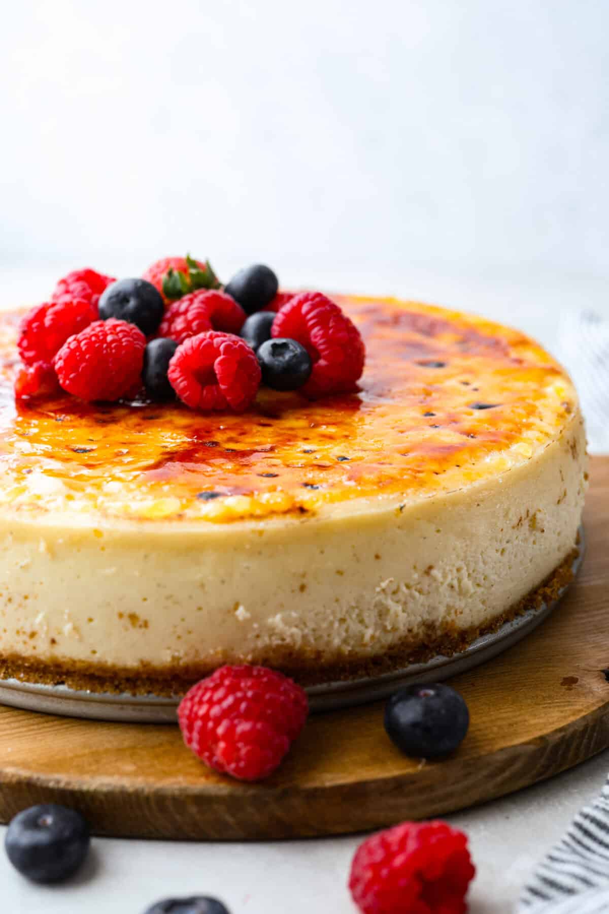 Creme brûlée cheesecake with fresh raspberries and blueberries on top.