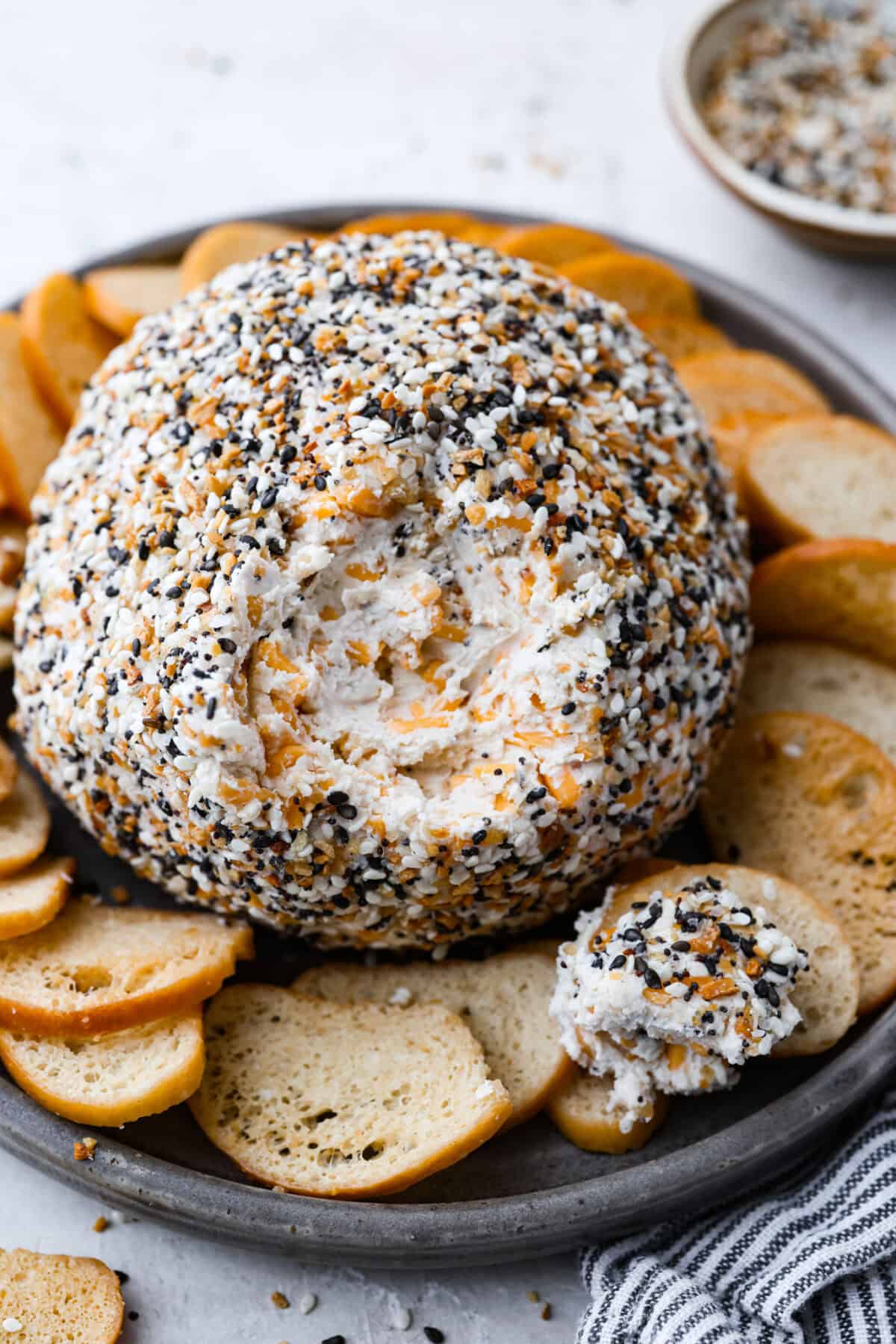 Angle shot of an everything bagel cheese ball on a platter.