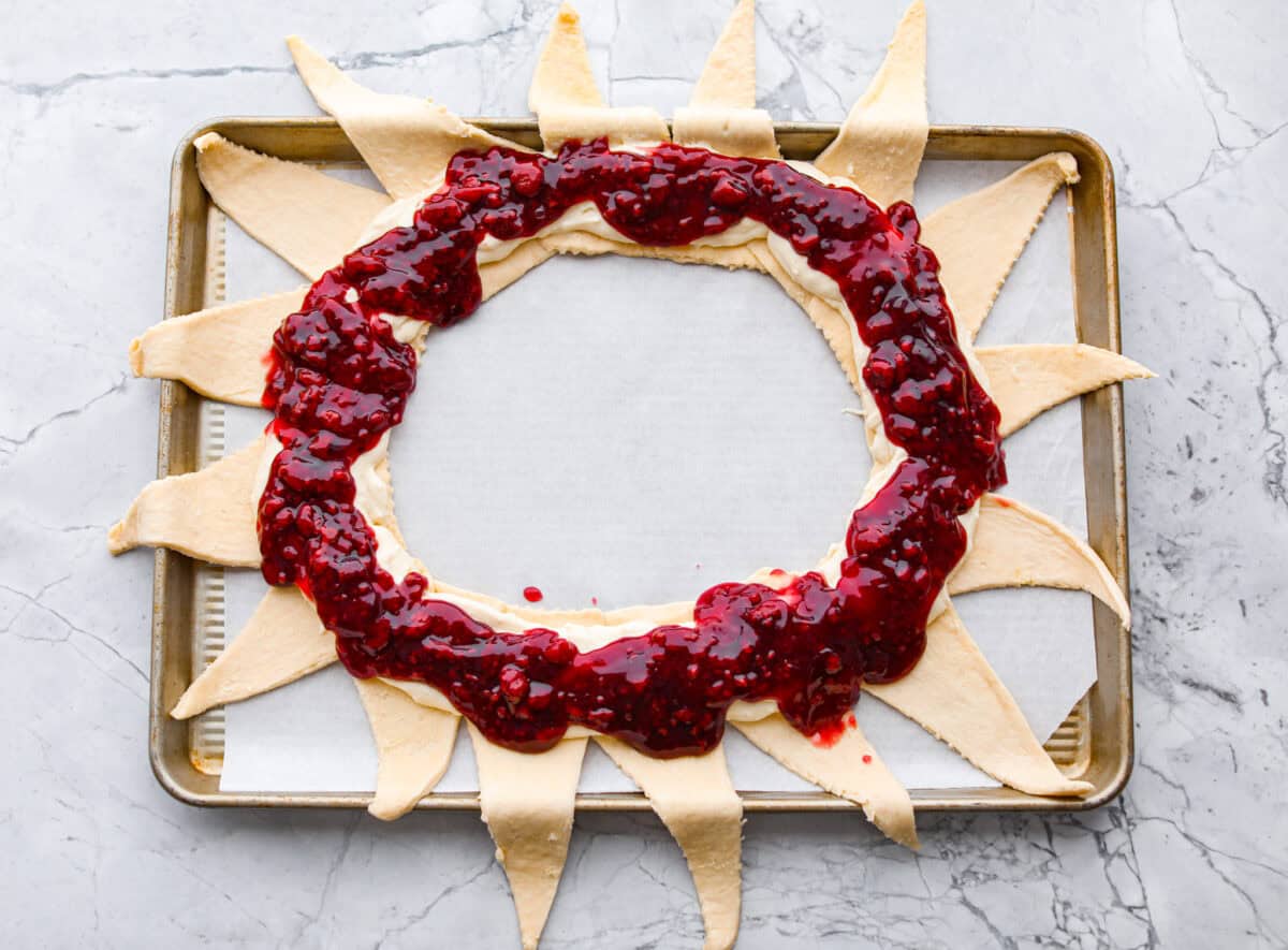 Overhead shot of the raspberry filling spread over the cream cheese and crescent rolls. 