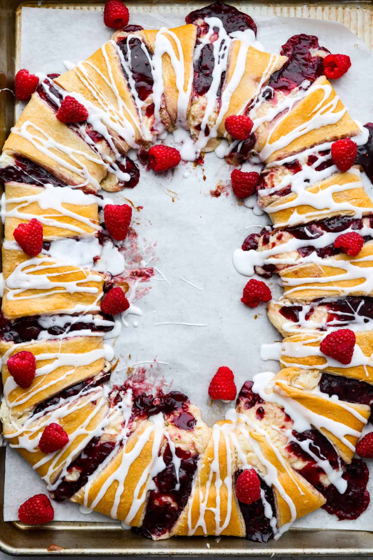 Overhead shot of the baked raspberry cream cheese crescent roll ring with whole fresh raspberries sprinkled around. 