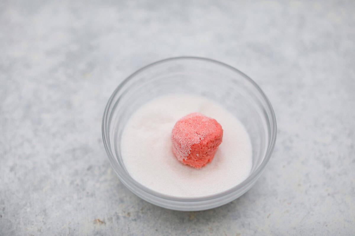 Angle shot of a ball of dough rolled in granulated sugar. 