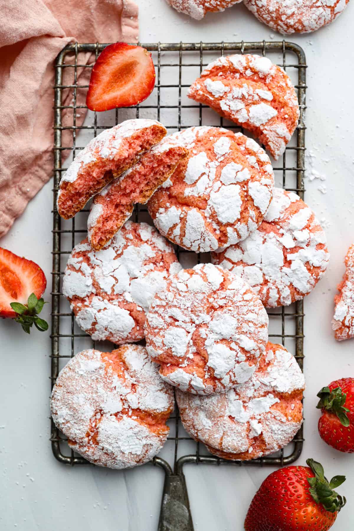 Overhead shot of strawberry crinkle cookies stacked on a cooling rack. 